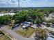 Wide aerial view of a property with a red building and a mobile home, surrounded by lush greenery and trees at 126 Ridgewood Ave, Brandon, FL 33510