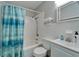 Bright bathroom with toilet, tub, sink, medicine cabinet, blue shower curtain, and white tiled walls at 126 Ridgewood Ave, Brandon, FL 33510