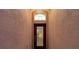 A close-up of the front door with textured walls and a transom window allowing natural light at 12831 White Bluff Rd, Hudson, FL 34669