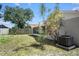 Backyard with manicured lawn, privacy fence, and tropical foliage with a peek at the enclosed lanai at 13613 Laraway Dr, Riverview, FL 33579