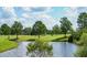 Picturesque view of a pond on a golf course, surrounded by trees, well-maintained landscaping and green grass at 13613 Laraway Dr, Riverview, FL 33579