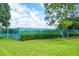 A well-maintained tennis court is surrounded by a green fence and lush landscaping, creating a private recreational area at 13613 Laraway Dr, Riverview, FL 33579