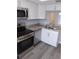 Kitchen with stainless steel appliances, shaker cabinets, granite countertops, and new grey flooring at 1415 Doolittle Ln # 104, Dunedin, FL 34698