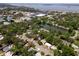 Aerial view of neighborhood with a pond, mature trees and view of the bay in the distance at 1443 Paloma Ln, Dunedin, FL 34698