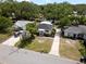 Aerial front view of single story home with dark roof, light paint, and well kept lawn and landscaping at 1443 Paloma Ln, Dunedin, FL 34698