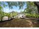Backyard with a large tree, grass, tropical landscaping and neutral colored home at 1443 Paloma Ln, Dunedin, FL 34698