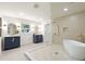 This bathroom features a soaking tub, glass enclosed shower, dual sink vanities and modern fixtures at 1443 Paloma Ln, Dunedin, FL 34698