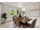 Bright dining room features modern light fixture, wood table with seating for six, and view to backyard at 1443 Paloma Ln, Dunedin, FL 34698