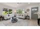 A modern living room featuring stylish seating, a glass coffee table, and views of the outdoor scenery through large windows at 1443 Paloma Ln, Dunedin, FL 34698