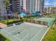 Aerial view of the basketball court alongside a tennis court with resort buildings and palm trees behind it at 1560 Gulf Blvd # 306, Clearwater Beach, FL 33767