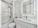 Bright bathroom featuring marble walls, glass shower door, and modern vanity with a light-up mirror at 1560 Gulf Blvd # 306, Clearwater Beach, FL 33767