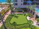 An artificial golf putting green between palm trees and resort buildings offer recreational opportunities at 1560 Gulf Blvd # 306, Clearwater Beach, FL 33767