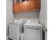 Functional laundry room with modern washer and dryer units, plus upper cabinets for storage at 19101 Marisa Ridge Pl, Tampa, FL 33647