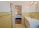 Bright bathroom with yellow tiling, a vanity and sink, connecting to the main bedroom with laminate flooring at 2071 Australia W Way # 59, Clearwater, FL 33763