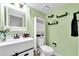This bathroom features a modern vanity, toilet with storage cabinet, and decorative shelves on a pale green wall at 3177 Montrose Pl, Palm Harbor, FL 34684