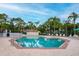 Community pool with a brick patio area, multiple lounge chairs, palm trees, and secure perimeter fencing at 3177 Montrose Pl, Palm Harbor, FL 34684