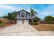 Two-story home featuring a two car garage, brick accents, a manicured lawn, and mature landscaping at 3177 Montrose Pl, Palm Harbor, FL 34684