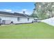 Well-maintained backyard featuring lush green grass, white fence, and a screened-in patio at 4302 Longfellow Dr, Plant City, FL 33566
