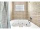 Close up of bathtub with tile surround and glass block window at 4302 Longfellow Dr, Plant City, FL 33566