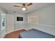 Bedroom with light blue walls, laminate floors, ceiling fan, television, and open door at 5081 72Nd N Ave, Pinellas Park, FL 33781