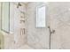 Detailed shot of the tile shower with marble-style tile, a shower head, and built-in shelving at 5235 42Nd S St, St Petersburg, FL 33711