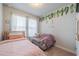 Cozy bedroom with a pink bed, loveseat, leafy decor, and natural light from two windows at 5538 Spanish Moss Cv, Bradenton, FL 34203