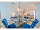 Dining area with blue velvet chairs, glass table, modern chandelier and view of living spaces at 5538 Spanish Moss Cv, Bradenton, FL 34203