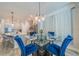 Dining area with blue velvet chairs, glass table, modern chandelier and view of the kitchen at 5538 Spanish Moss Cv, Bradenton, FL 34203