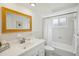 Bright bathroom featuring a single vanity, framed mirror, and a shower-tub combination, complete with white tiling at 5620 Perkin Dr, New Port Richey, FL 34652