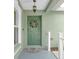 View of a green front door with decorative wreath, hanging light fixture and adjacent window at 5825 Meadowpark Pl, Lithia, FL 33547