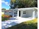 Beautiful gray single-story home with a manicured lawn and a paved driveway leading to a carport at 6507 N 21St St, Tampa, FL 33610
