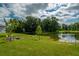 Spacious backyard with lush green grass extending to the water's edge, complemented by a cozy fire pit area at 7154 Steer Blade Dr, Zephyrhills, FL 33541