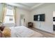 Cozy bedroom featuring hardwood floors, a large flat-screen TV, and ample natural light from the window at 7154 Steer Blade Dr, Zephyrhills, FL 33541