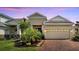 Charming single-Gathering home with brick driveway, two-car garage, manicured lawn, and lush tropical landscaping at 7423 Sungold Meadow Ct, Apollo Beach, FL 33572