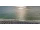 Serene beach view with glistening water, soft sand, beachgoers and many umbrellas at 94 Devon Dr, Clearwater Beach, FL 33767