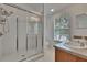 Bathroom featuring double sinks, a walk-in shower with glass door, and a bright window at 9506 Harpender Way, Tampa, FL 33626