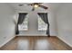 Spacious bedroom with wood-look flooring, a ceiling fan, and two windows with gray curtains at 9506 Harpender Way, Tampa, FL 33626
