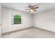 Bedroom with carpet flooring, a ceiling fan, and a window providing natural light and green outdoor views at 9812 N Pawnee Ave, Tampa, FL 33617