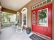 Inviting front porch with white rocking chairs and a vibrant red door at 10309 Marchmont Ct, Tampa, FL 33626