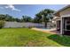 Backyard showcases a sparkling pool, enhanced by the lush green lawn, privacy fence, and mature trees creating a peaceful outdoor retreat at 1041 Persimmon Dr, Palm Harbor, FL 34683