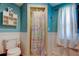 Cozy blue bathroom with wainscoting, decorative shelving, and shower with colorful patterned curtain at 1041 Persimmon Dr, Palm Harbor, FL 34683