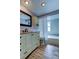 Stylish bathroom featuring a large mirror, white cabinets, and wood-look flooring at 1041 Persimmon Dr, Palm Harbor, FL 34683