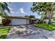 Charming single-story home featuring an attached two-car garage, mature landscaping, and inviting curb appeal at 1041 Persimmon Dr, Palm Harbor, FL 34683