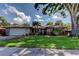 Charming single-story home boasts a lush lawn, mature trees, and a two-car garage at 1041 Persimmon Dr, Palm Harbor, FL 34683