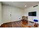 Bright living room with wood floors, television on the wall, small dining table, and blue stool at 1115 Rue Des Chateaux # 2B, South Pasadena, FL 33707