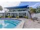 Community pool with covered seating area, lush landscaping, and steps leading into the pool at 1115 Rue Des Chateaux # 2B, South Pasadena, FL 33707