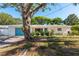Charming single-story home with a light blue door and one-car garage door complemented by mature trees and landscaping at 1152 Jackmar Rd, Dunedin, FL 34698