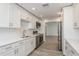 Bright kitchen with white cabinets, stainless steel appliances, stone countertops, and wood-look floors, creating a clean and modern look at 1152 Jackmar Rd, Dunedin, FL 34698