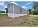 Exterior side view of a gray mobile home with a wooden porch on a large grassy lot at 16137 Melbourne St, Brooksville, FL 34604