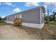 Gray sided mobile home with white trim featuring a wooden porch under a partly cloudy blue sky at 16137 Melbourne St, Brooksville, FL 34604